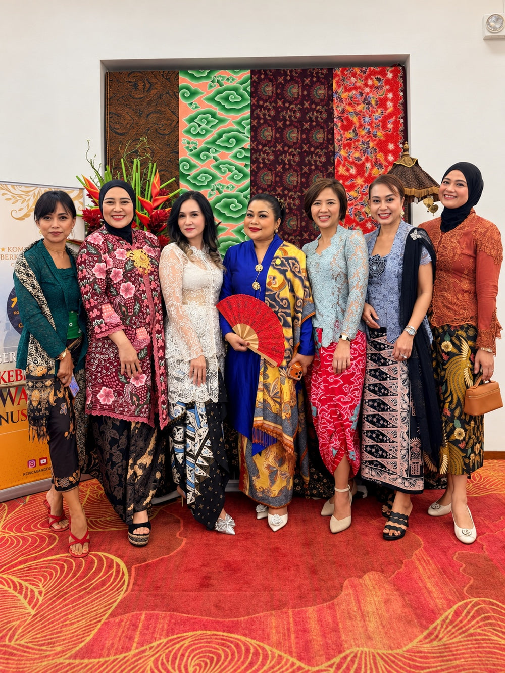 Seven women wearing kebaya and batik at a cultural gathering.